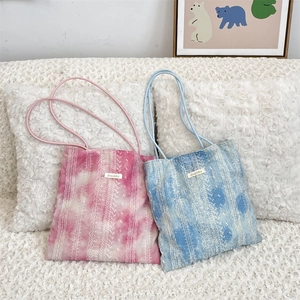 Detailed close-up of pink and blue tie-dye tote bags with intricate white embroidery