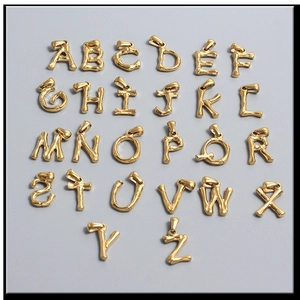 Macro view of gold bamboo texture alphabet charms from A to Z with lobster clasps