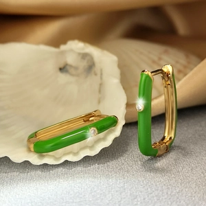 Macro shot of gold rectangle hoop earrings with green enamel and a small cubic zirconia stone