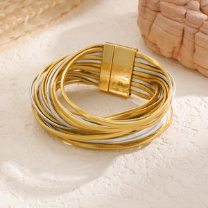 Detail of layered gold and silver cord bracelet with a wide magnetic clasp closure