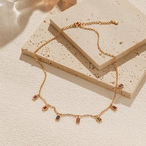 Detail of 18K gold plated necklace with colorful rectangular zircon gemstones on stone
