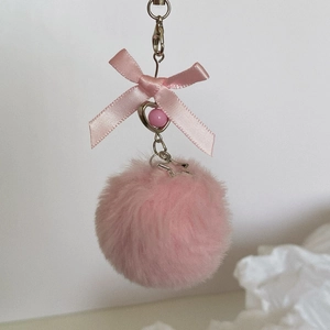 Detail of pink faux fur ball keychain with satin bow and heart-shaped pendant