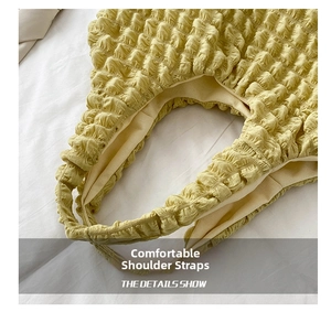 Detail of the lemon yellow pleated strap on the shoulder bag with bubble texture