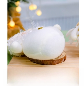 Close-up of white plush sheep Christmas ornament with gold ring on rustic wood base