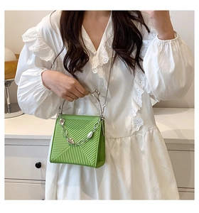 Detail of lime green pleated handbag with silver metallic handle and chunky chain accent