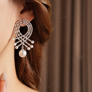 Gros plan d'une boucle d'oreille en argent avec cristaux et multiples perles blanches