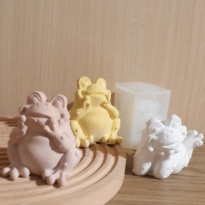 Detailed silicone mold with finished frog sculptures on a wooden display tray