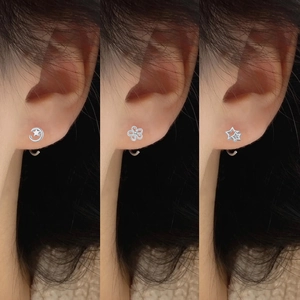 Detail shot of three silver S999 hollow cat-shaped earring studs worn on the ear