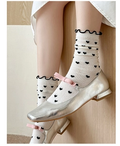 Detail of white crew socks with black heart pattern and ruffled lace cuffs for women