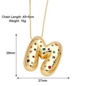 Macro shot of letter M pendant with colorful zircons and polished gold finish