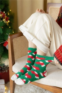Christmas coral fleece socks with festive patterns on model beside a holiday tree