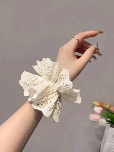 Detail of white lace scrunchie with intricate eyelet embroidery and scalloped edges