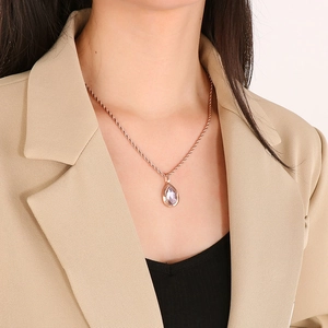 Close-up of a rose gold teardrop necklace with a clear crystal pendant on a model
