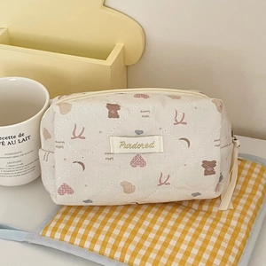Borsa cosmetica trapuntata beige con orsetto e cuori su tappetino a quadri gialli