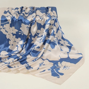 Detailed view of blue and beige floral silk scarf showing smooth texture and sheen