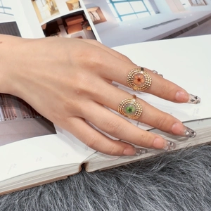 Detailed view of adjustable gold rings with floral motifs and bead texture on fingers