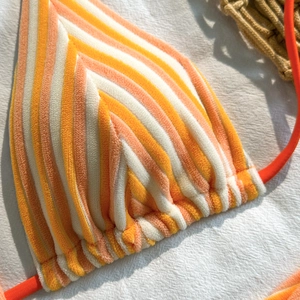 Detail of striped terry fabric bikini top with ruched edges and peach orange stripes