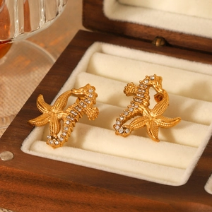 Gros plan de boucles d'oreilles hippocampe dorées avec zircons blancs dans un coffret