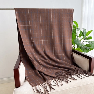 Detail of soft brown plaid scarf with tassels draped on a chair in a cozy room