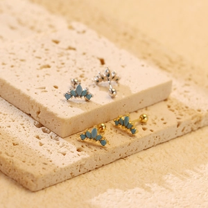Detail of crown earrings with turquoise marquise stones in gold and silver finishes