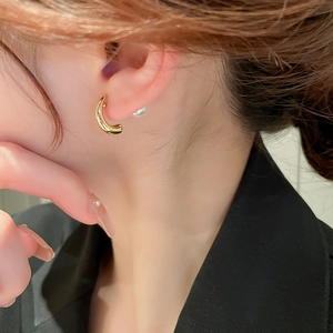 Detail of elegant gold geometric hoop earrings with pearl backings on model