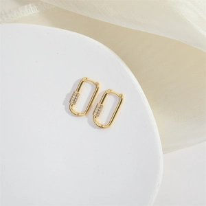 Macro shot of gold rectangle earrings with cubic zirconia stones on white display