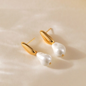 Macro detail of 18K gold-plated irregular turquoise and Baroque pearl drop earrings