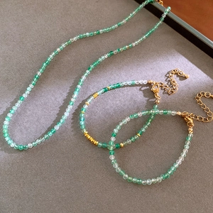 Detail view of green beaded necklace and bracelets with gold accents on velvet