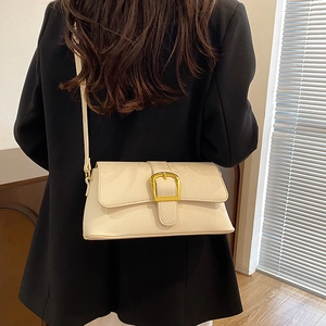 Model wearing a cream PU leather baguette bag with lychee texture and gold buckle detail