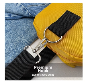 Detail of sturdy silver metal swivel hook and black woven strap on a yellow nylon handbag