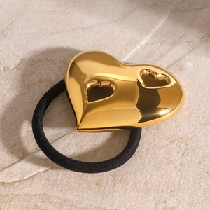 Golden chunky heart hair tie with hollow design on natural stone background