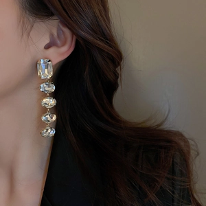 Macro detail of long silver fringe earrings with five geometric clear gemstones on a model