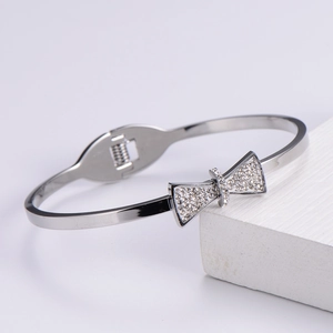 Close-up of a silver bow bracelet with sparkling zircons on a white geometric stand