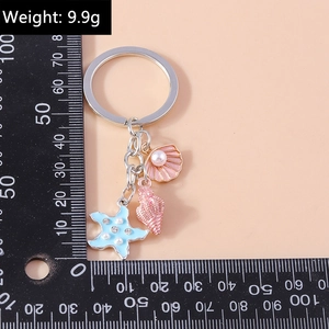 Detail of seashell and starfish keychain charms with scale showing a length of 10cm