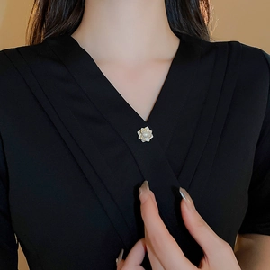 Detail of flower brooch with white petals and a pearl on a black blazer jacket