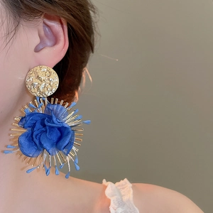 Macro detail of royal blue chiffon flower earrings with golden radiating metallic accents