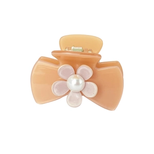 Detail of peach hair claw clip with bow shape, pink flower and central white pearl