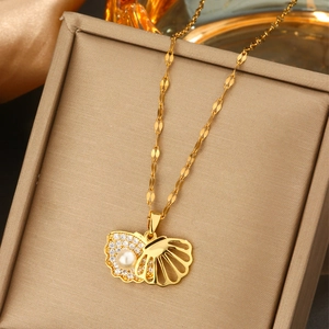 Detailansicht goldener Muschel-Anhänger mit Kristallen und Perle auf einer Schmuckbox