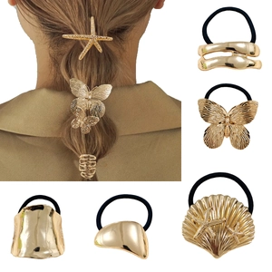 Dettaglio di ciondoli a farfalla e stella marina dorati su elastici per capelli alla moda