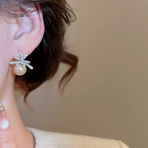 Close-up of elegant flower zircon earrings with round white pearls on a model's ear