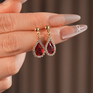 Close-up of luxury red teardrop earrings with shimmering rhinestones and gold base