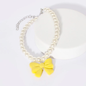 Detailed view of white pearls and yellow resin bow pendant on a pet necklace charm