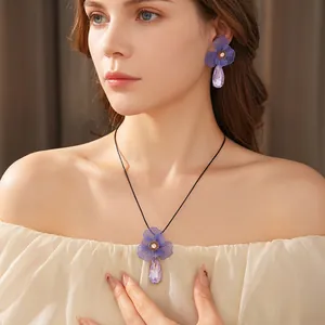 Elegant purple flower necklace and earring set with teardrop crystals worn by model