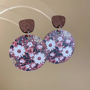 Gros plan sur les boucles d'oreilles rondes en bois avec motif marguerites et fleurs