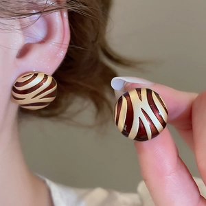 Close-up of geometric round enamel earrings with red and gold wavy zebra patterns