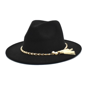 Detail eines schwarzen Woll-Fedoras mit Goldkette, weißen Perlen und hängender Quasten-Deko