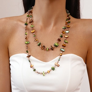 Detail of bohemian layered necklace with green and brown irregular stone beads on model