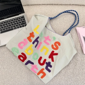 Detailed embroidery of 'Let's think about earth' and woven rope handle on canvas tote