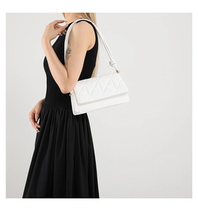 Close-up of white quilted geometric crossbody bag with knot strap and gold hardware
