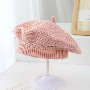 Detail of pink knitted girl's beret with elegant pearl accents and ribbed texture